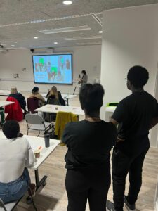 Audience members watch Savera UK Youth Advisory Board member Adele discuss the filmmaking process of the Orange Brick Road project
